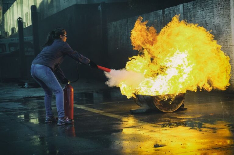 A person reading fire extinguisher labels on a red wall-mounted extinguisher in a residential hallway.