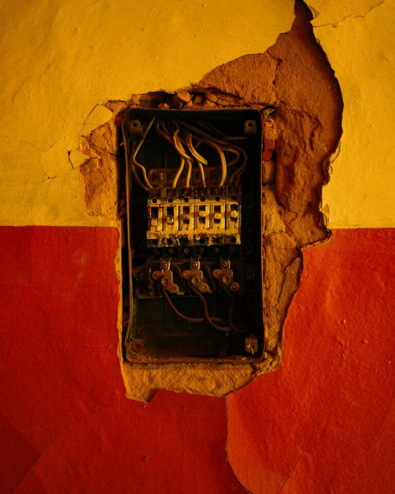 A hand checking a wall electrical outlet for heat or discoloration inside a typical residential living room.
