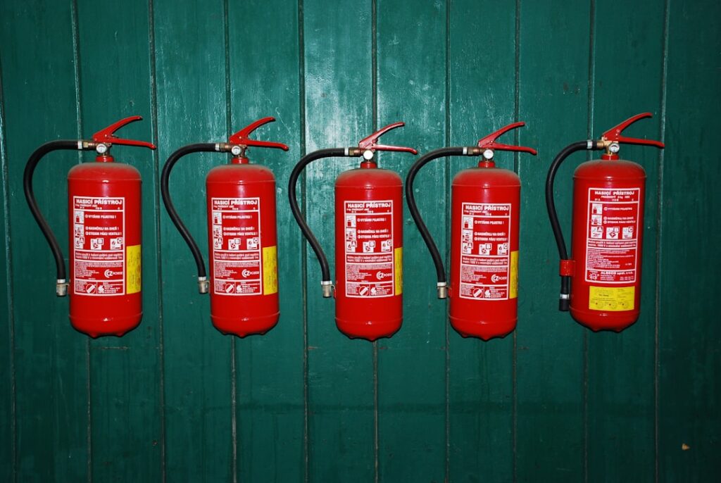 A person using a red fire extinguisher to put out a small fire in a residential kitchen setting.
